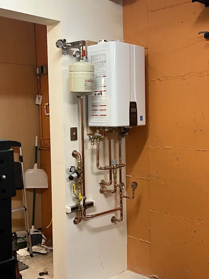 Plumbing technician inspecting water heater connections in Norton